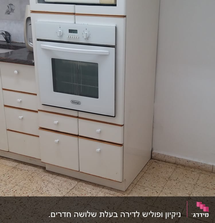 מטבח עם תנור ומיקרוגל על ארונות לבנים